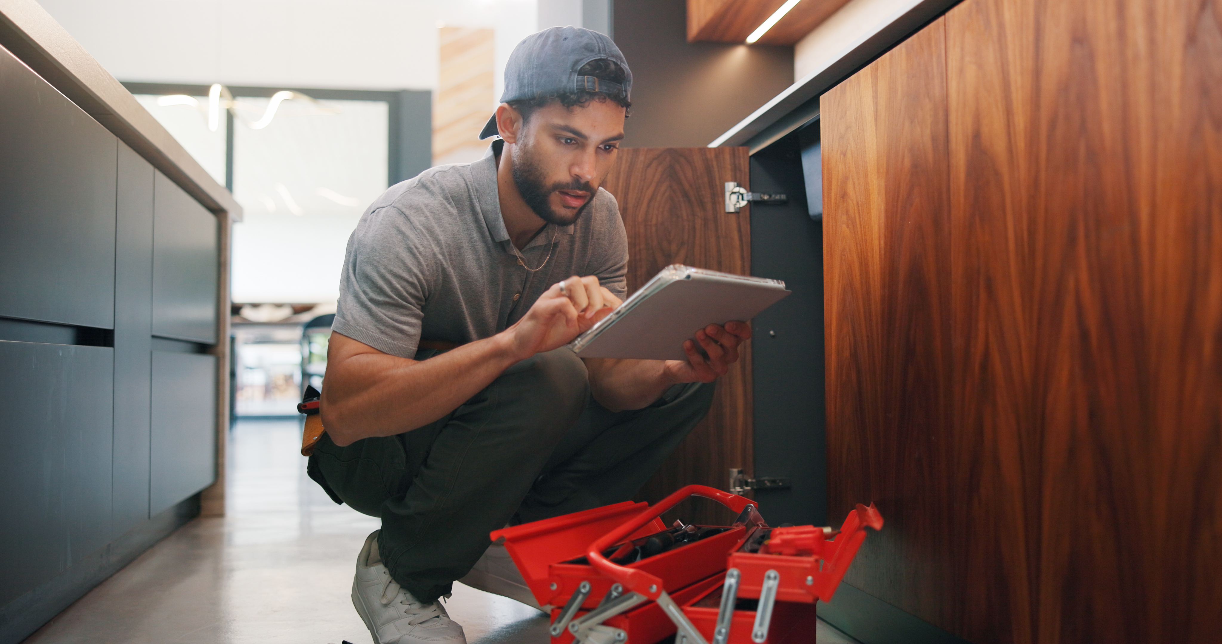 Plumber, man and maintenance in kitchen with tablet, inspection and review for quality assurance. Handyman, person and scroll in house with tech, plumbing checklist or report for restoration project.